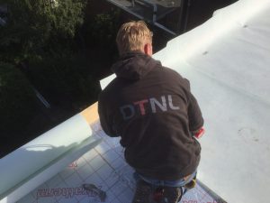 Jongeman werkend aan witte dakbedekking